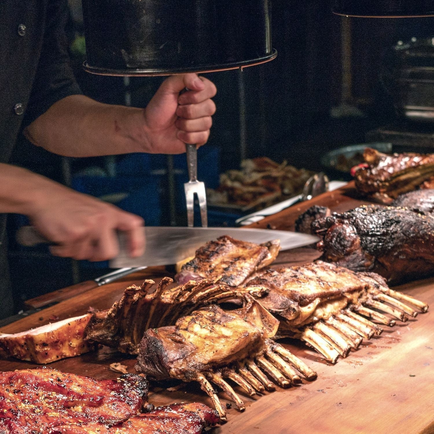 A selection of different cuts of lamb on a cutting board, including tenderloin, shank, rack of lamb, shoulder, and chops.
